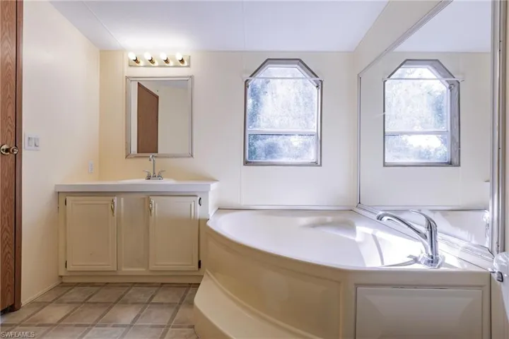 Bathroom with tile patterned floors, a bath, and vanity