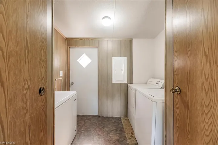Laundry area featuring separate washer and dryer, dark tile patterned floors, and electric panel