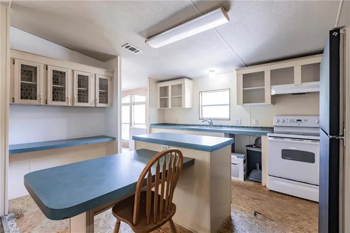 Kitchen featuring electric range, a center island, fridge, and a textured ceiling