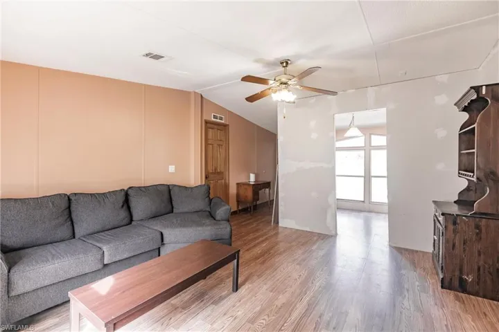 Living room featuring lofted ceiling, hardwood / wood-style flooring, and ceiling fan
