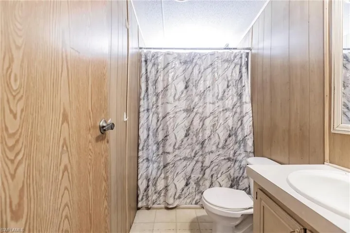 Bathroom featuring tile patterned flooring, toilet, vanity, and a textured ceiling