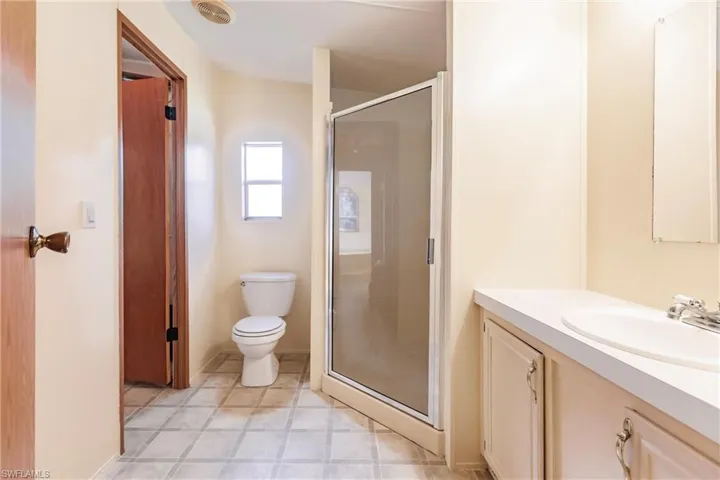 Bathroom featuring a shower with shower door, vanity, tile patterned flooring, and toilet