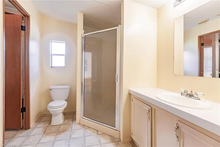 Bathroom featuring walk in shower, tile patterned floors, toilet, and vanity