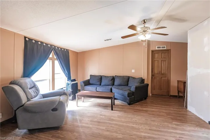 Living room featuring wood-type flooring, vaulted ceiling, and ceiling fan