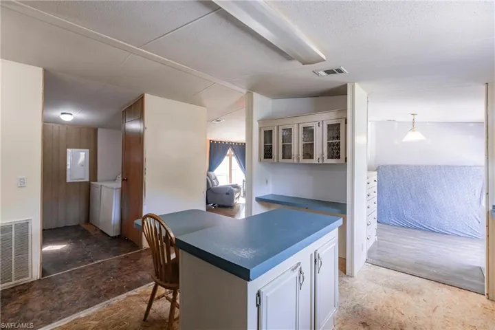 Kitchen with washing machine and clothes dryer, white cabinetry, a kitchen breakfast bar, and lofted ceiling