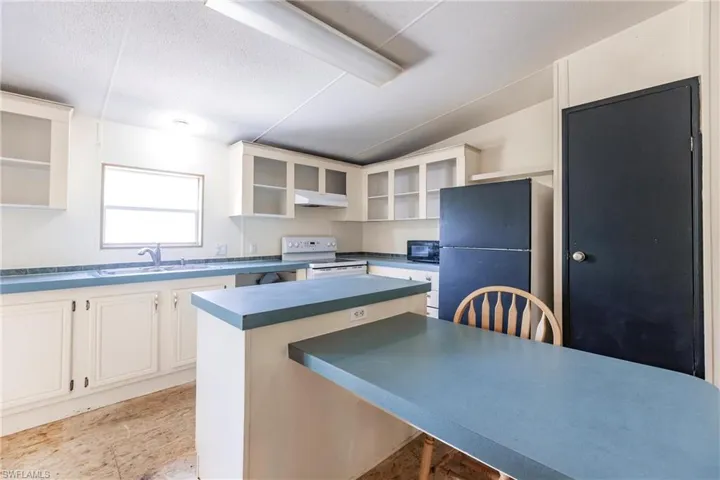 Kitchen with black appliances, white cabinets, sink, a kitchen island, and light tile patterned floors