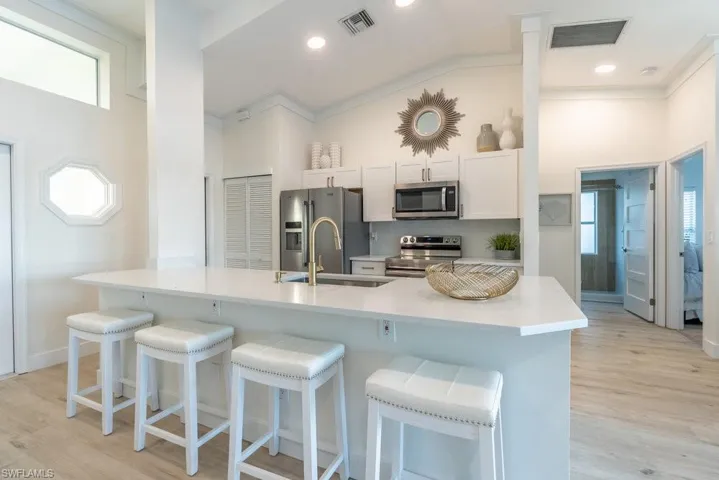 Kitchen features stainless appliances, pantry, island with quartz counters and a charming port hole window to bring in a coastal flair