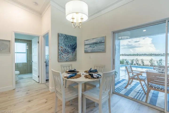 Dining area features views of the pool and lake beyond, a modern chandelier and sliding doors that lead out to the lanai.