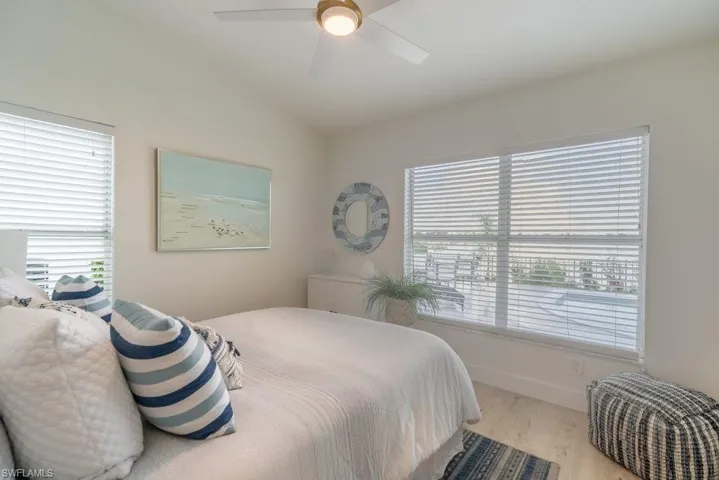 Coastal style guest bedroom with new modern ceiling fan, double closet and lofted ceiling with views of the lake