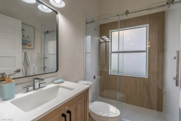 Guest Bathroom serves two bedrooms and features walk in shower with beautiful new tile accent wall, toilet, and new vanity, new mirror and new vanity lighting, luxury vinyl plank flooring
