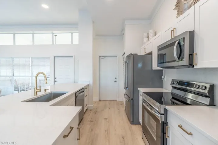 Kitchen features white cabinetry, stainless steel a