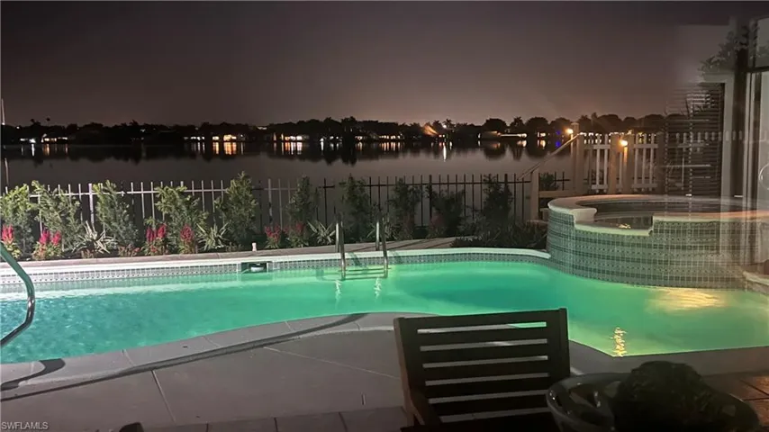 Pool at twilight featuring an in ground hot tub