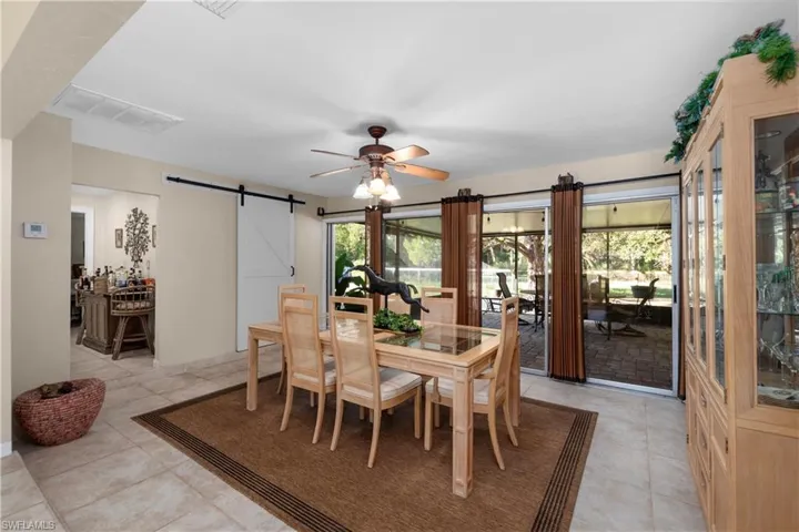 Tiled dining space with ceiling fan and a barn door