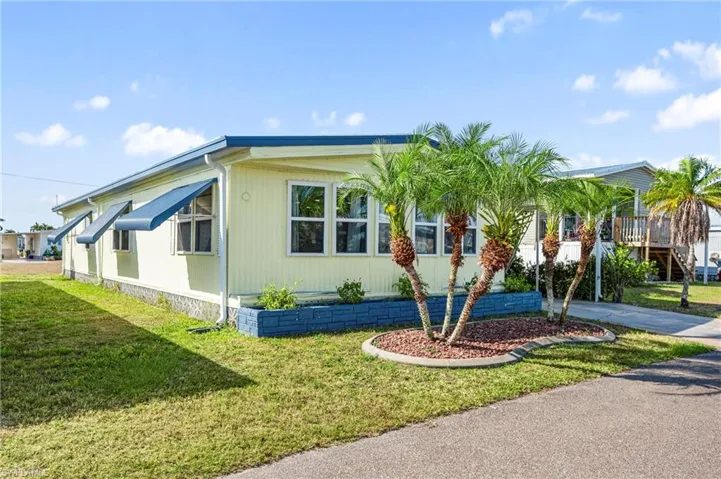 View of property exterior with concrete driveway and a lawn