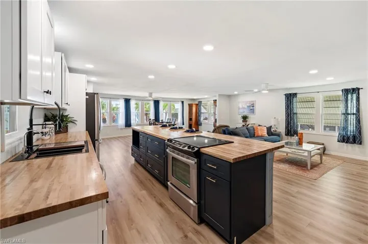 Kitchen featuring butcher block countertops, white cabinets, dark cabinetry, appliances with stainless steel finishes, and a sink