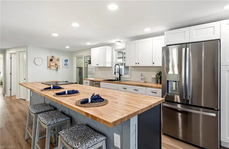 Kitchen featuring white cabinets, a sink, wood counters, stainless steel appliances, and a breakfast bar area