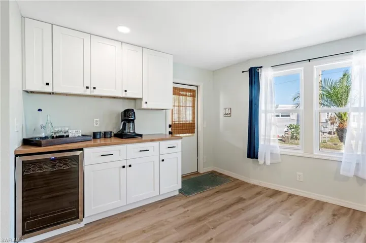 Bar featuring light wood-type flooring, baseboards, recessed lighting, a dry bar, and wine cooler