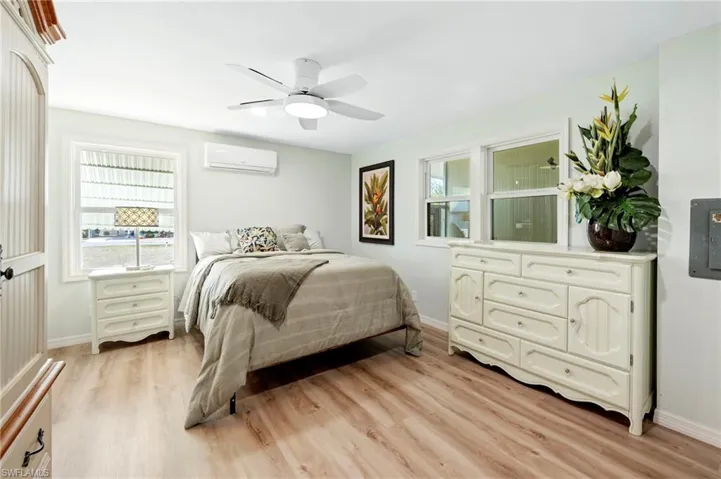 Bedroom featuring baseboards, light wood-type flooring, and a wall unit AC