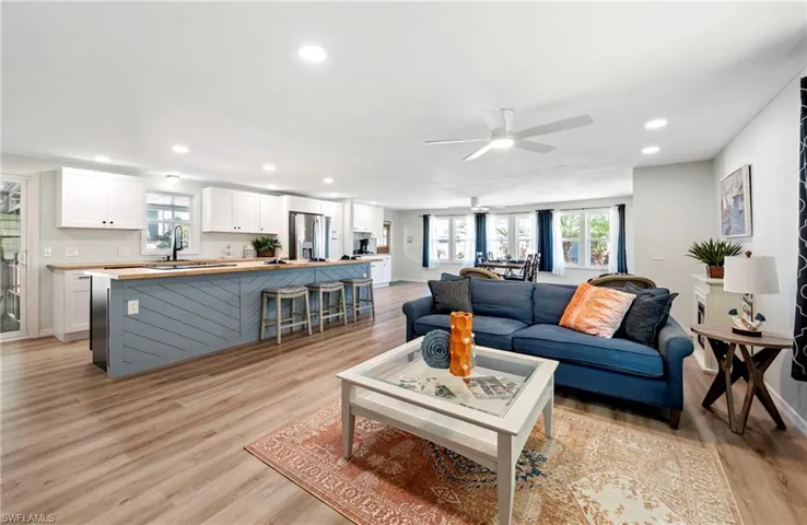 Living room with light wood-style flooring, ceiling fan, and recessed lighting