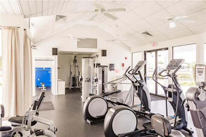 Gym featuring high vaulted ceiling, a ceiling fan, and visible vents