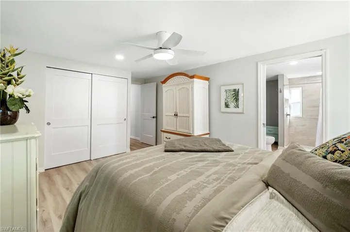 Bedroom with a closet, ensuite bathroom, ceiling fan, recessed lighting, and light wood-style flooring