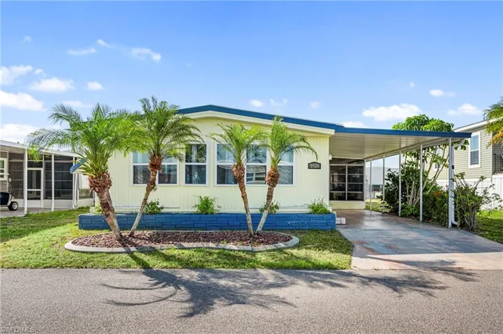 Manufactured / mobile home featuring an attached carport, a sunroom, and concrete driveway