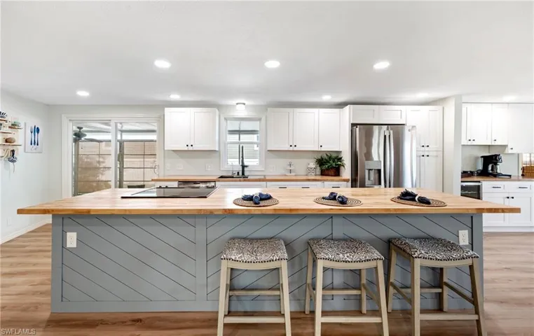 Kitchen featuring a kitchen breakfast bar, white cabinetry, a sink, stainless steel fridge, and butcher block countertops