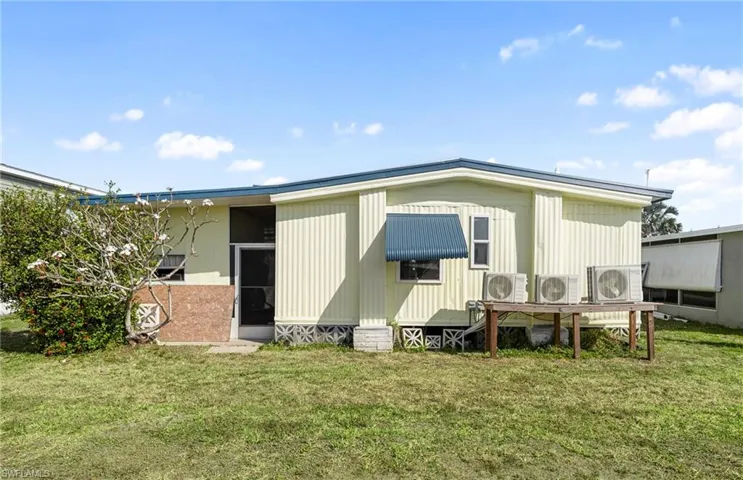 Back of house with a lawn and ac unit