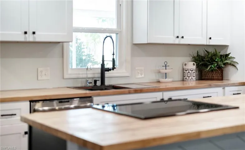 Kitchen featuring white cabinets, black electric cooktop, a sink, and a healthy amount of sunlight