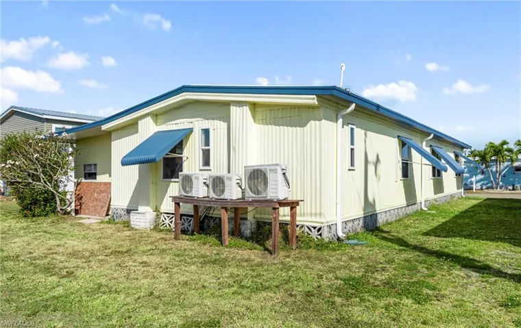 Rear view of property with ac unit and a lawn