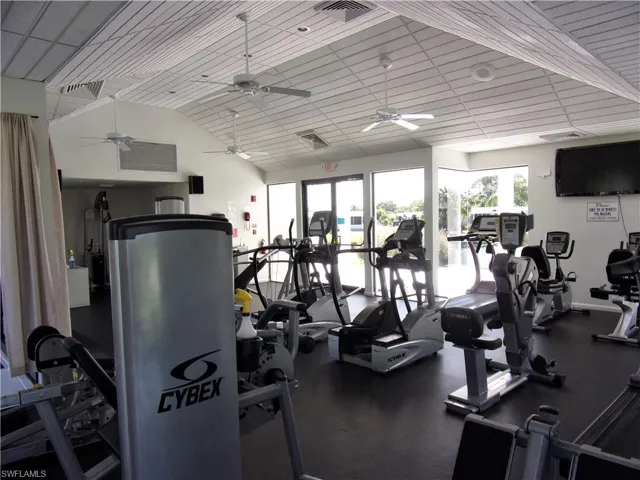 Gym with visible vents, a ceiling fan, and lofted ceiling
