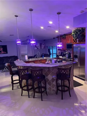 Indoor wet bar featuring refrigerator, decorative light fixtures, and recessed lighting