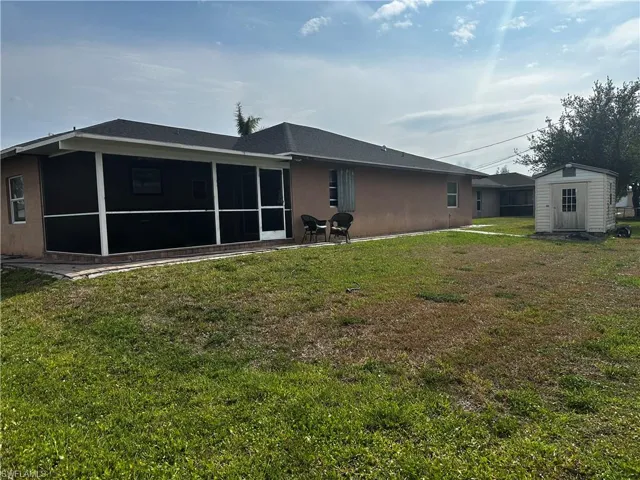 Rear view of property with a shed, a sunroom, an outdoor structure, and a yard