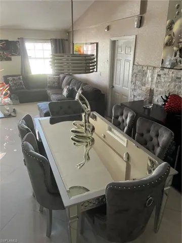 Tiled dining area featuring lofted ceiling and a textured wall