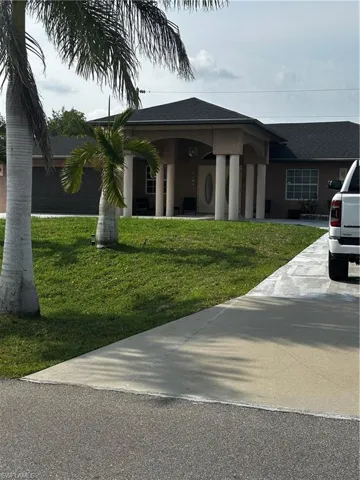 Ranch-style home featuring a front lawn, driveway, and roof with shingles