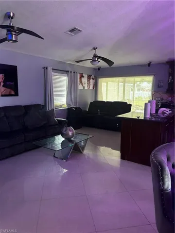 Living room with a ceiling fan, healthy amount of natural light, a textured ceiling, and light tile patterned flooring