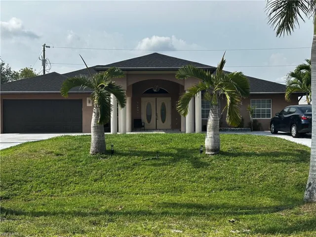 View of front of house with concrete driveway, a front yard, an attached garage, and stucco siding