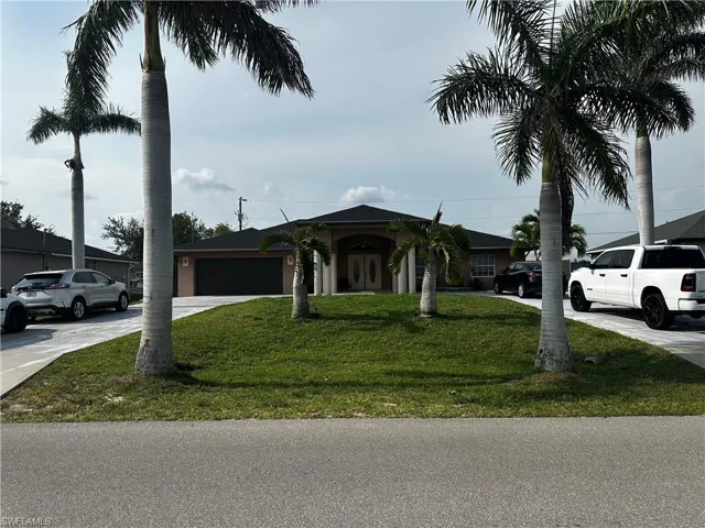 Ranch-style house featuring concrete driveway, a front yard, an attached garage, and french doors