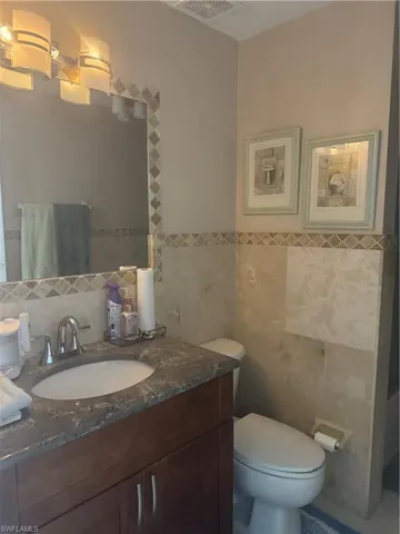 Bathroom featuring tile walls, toilet, and vanity