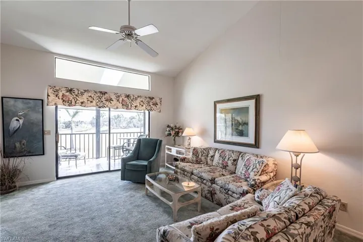 Carpeted living room featuring high vaulted ceiling and ceiling fan