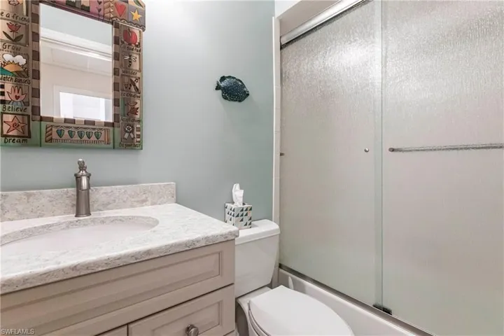 Guest Full bathroom with enclosed tub / shower combo, vanity, and toilet