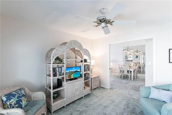 Carpeted living room with ceiling fan with notable chandelier