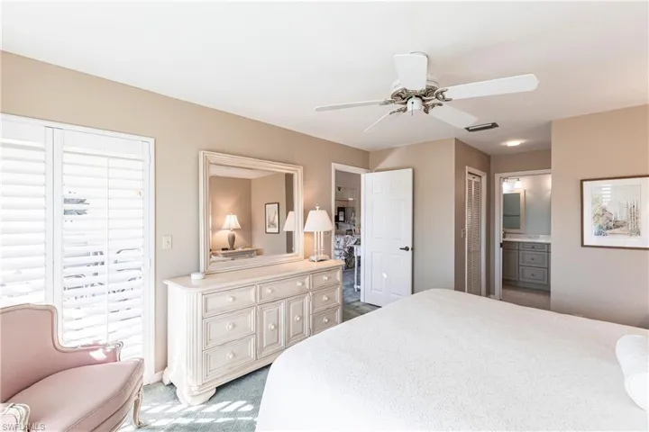 Carpeted bedroom with connected bathroom and ceiling fan