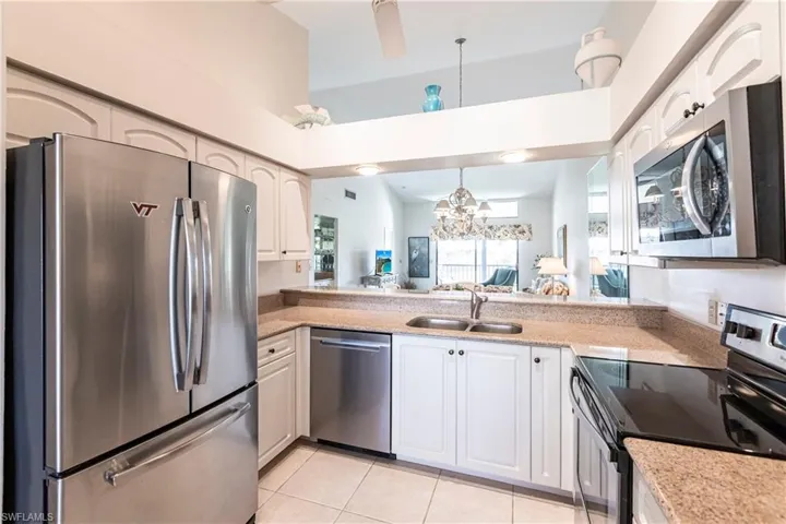 Kitchen with sink, light tile patterned flooring, white cabinets, and appliances with stainless steel finishes