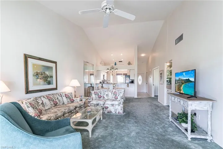 Living room featuring ceiling fan, dark carpet, and high vaulted ceiling