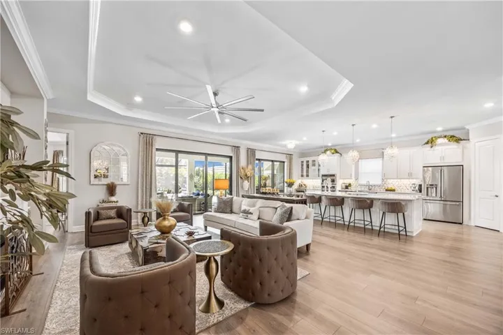 Living room featuring light hardwood / wood-style flooring, a tray ceiling, ceiling fan, and ornamental molding