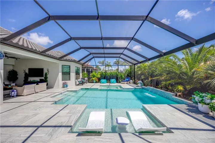 View of swimming pool featuring pool water feature, a patio, glass enclosure, and an in ground hot tub