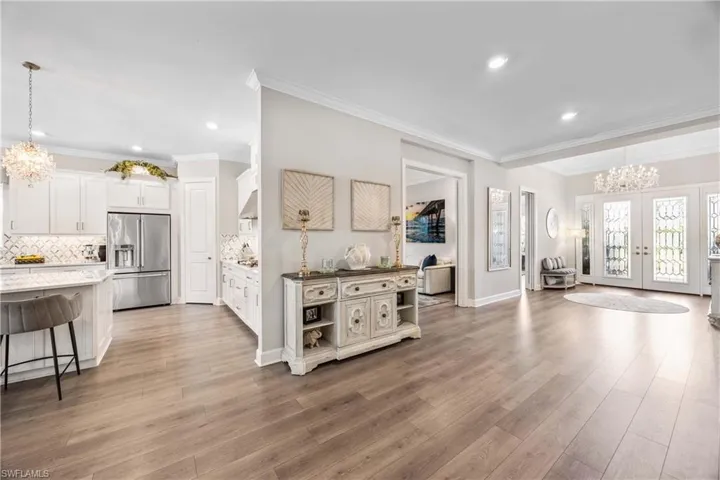 Kitchen featuring white cabinets, high end fridge, decorative light fixtures, an inviting chandelier, and hardwood / wood-style floors
