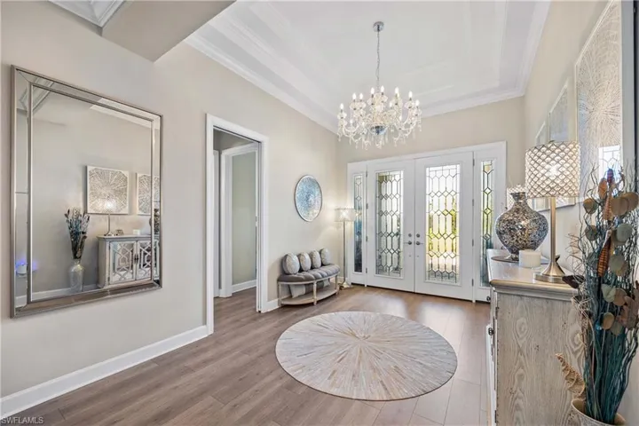 Entrance foyer featuring french doors, ornamental molding, hardwood / wood-style flooring, and a notable chandelier