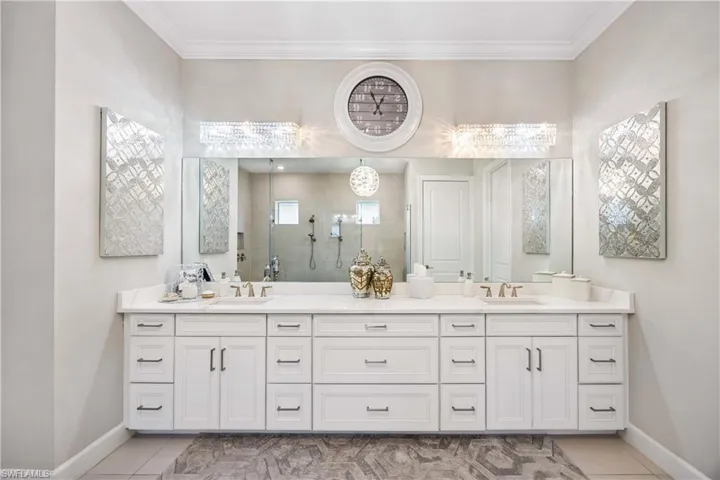 Bathroom featuring walk in shower, crown molding, vanity, and tile patterned floors